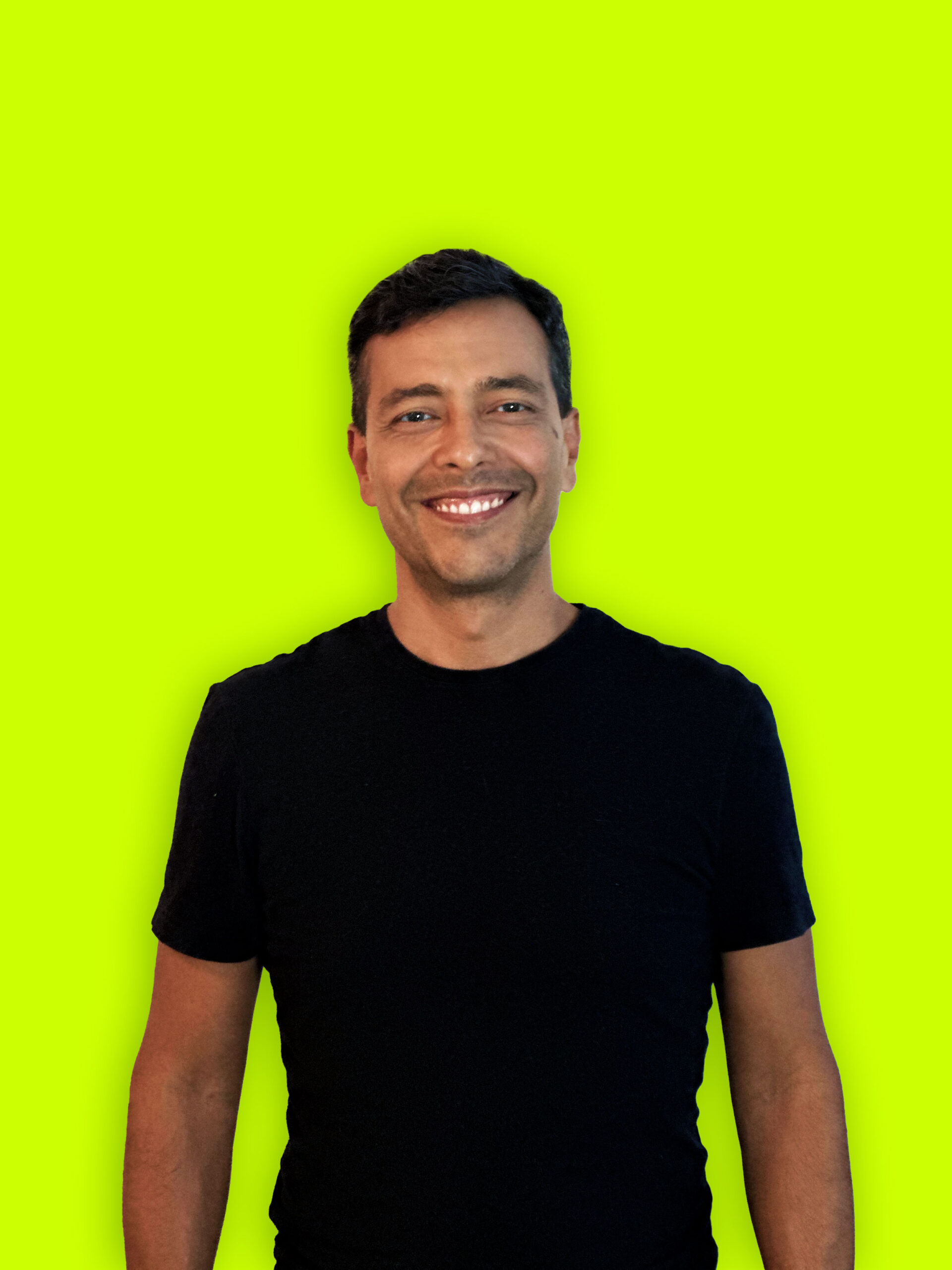 Smiling man in black t-shirt against bright yellow background.