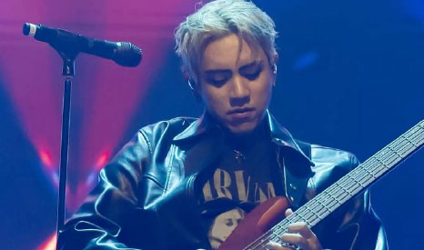 Musician playing bass guitar on stage.